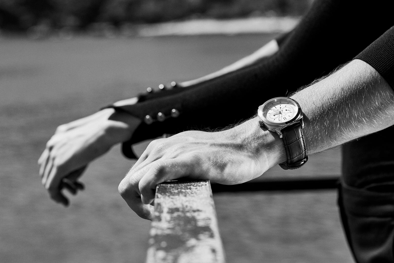 Hands resting on a stone balustrade, a watch on the wrist