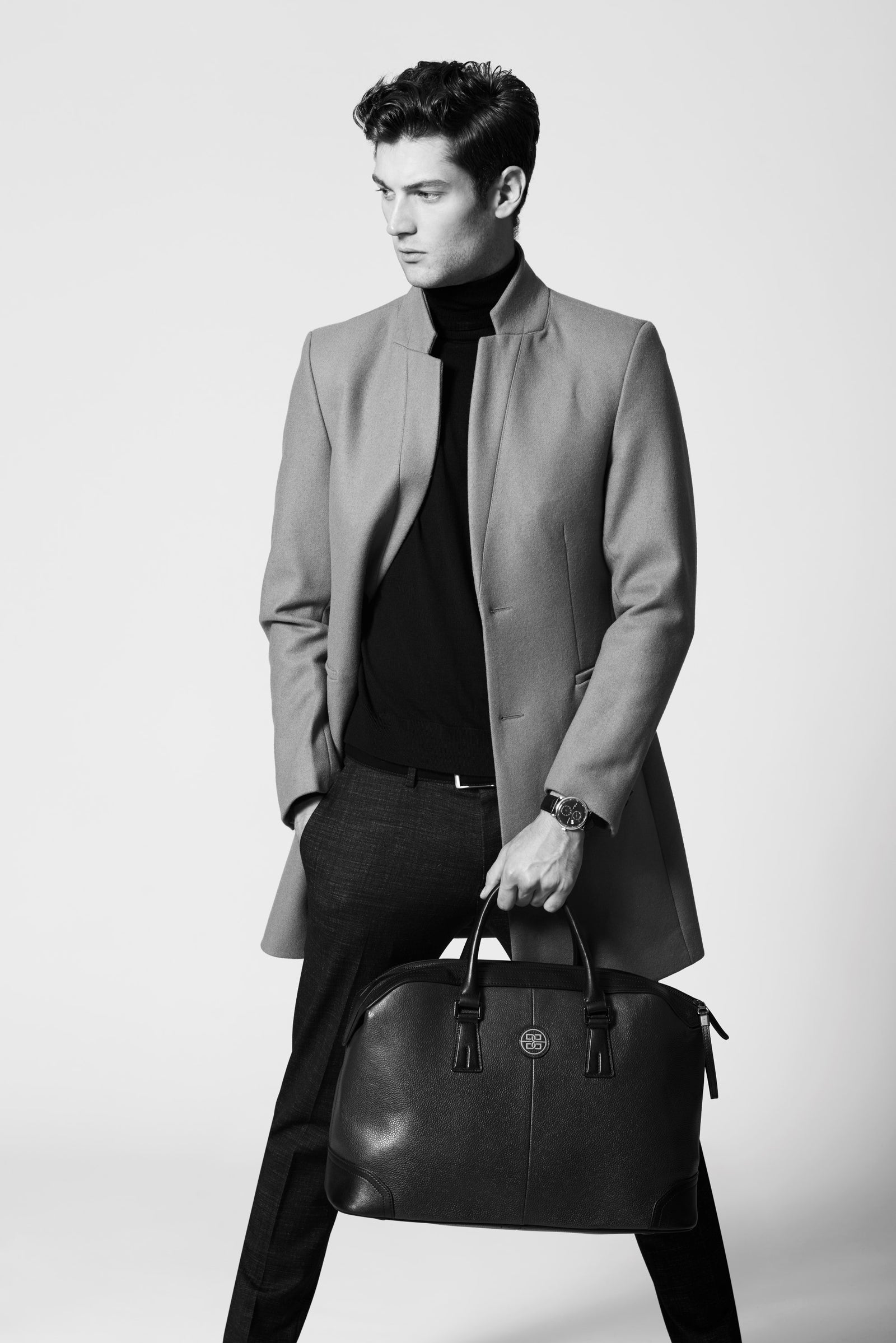 A man in a grey coat carrying a leather bag