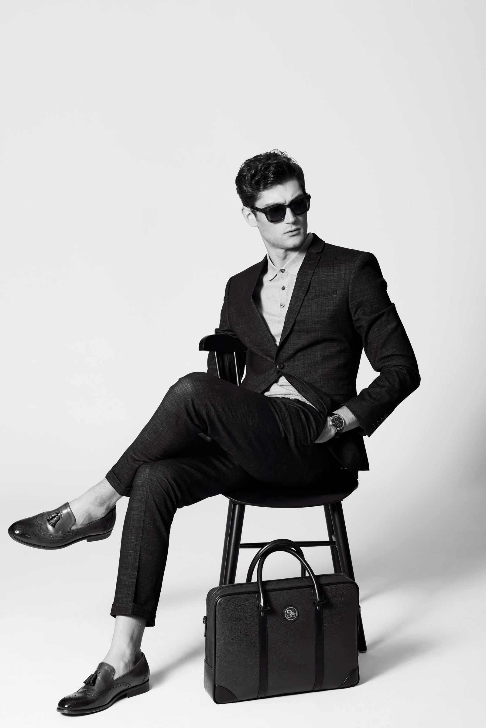 A man seated on a stool beside a briefcase