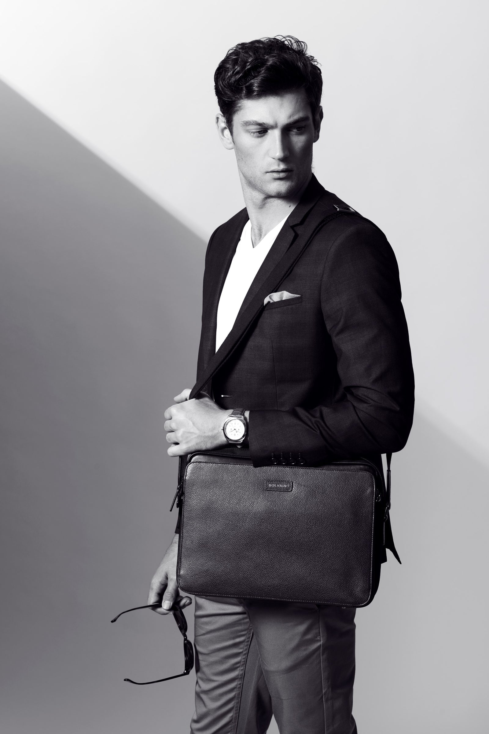 A man in a blazer carrying a leather satchel