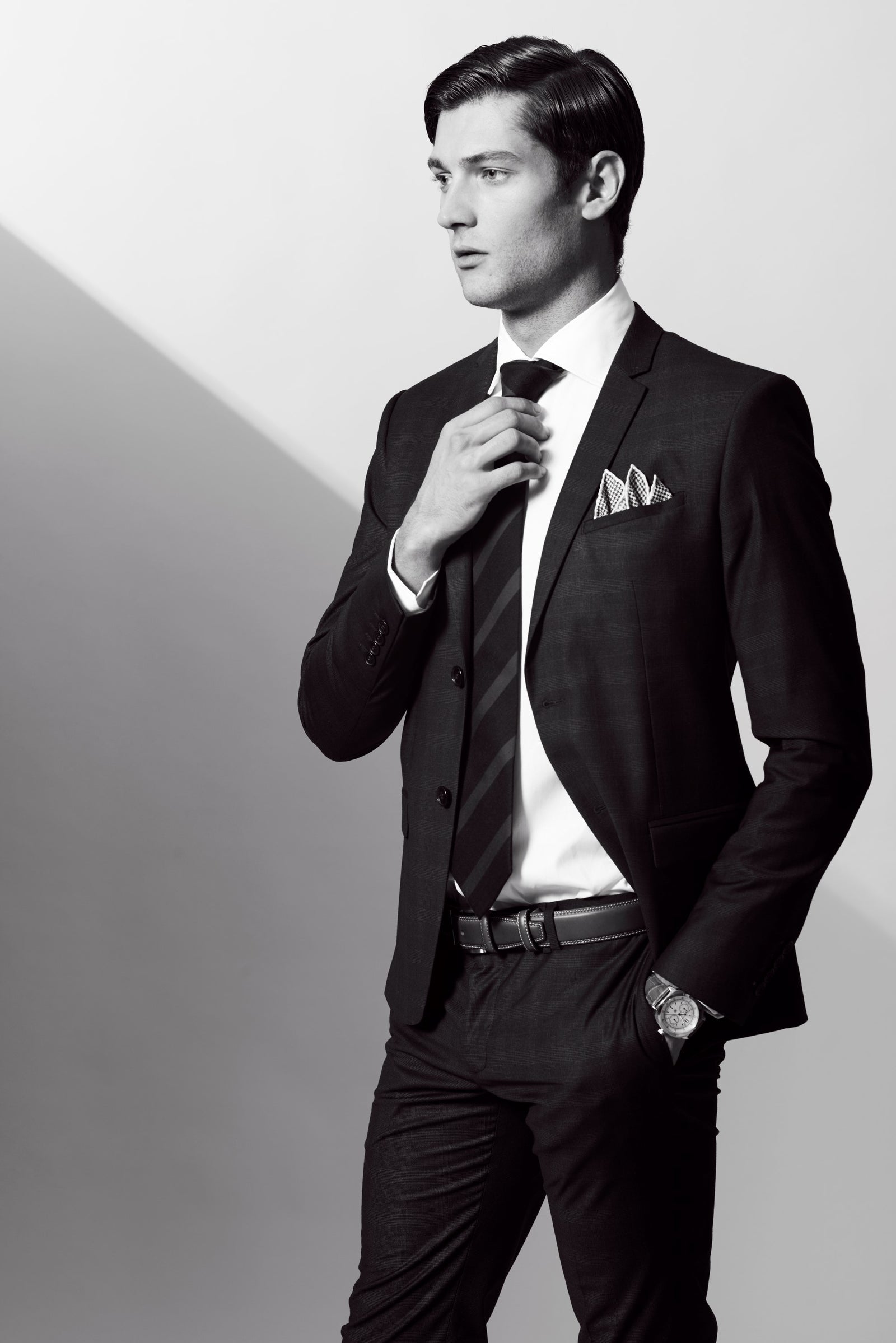 A man in a suit adjusting his tie