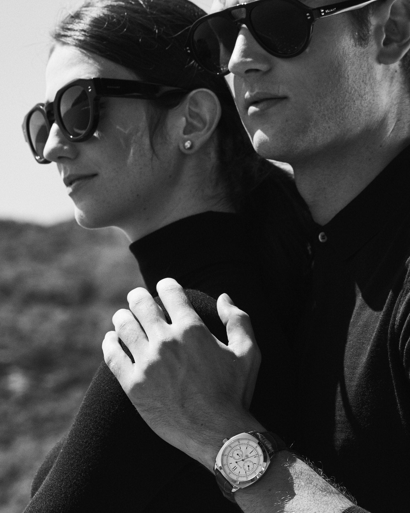 A couple in sunglasses, his hand on her shoulder, a Bolvaint watch on his wrist